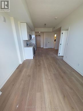 Brantford condo for rent - A real estate listing photo of a large empty room with wood flooring.