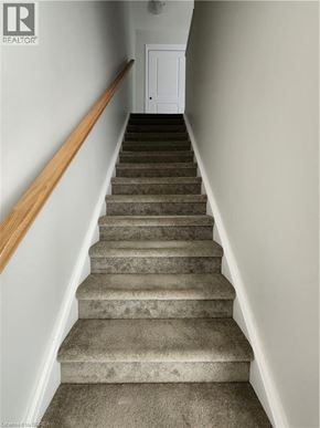Kitchener condo for rent - A set of stairs with a wooden handrail leading to a white door.