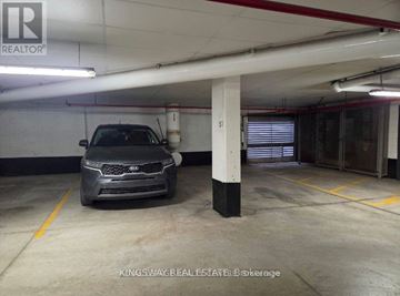 Oakville (Ro River Oaks) townhouse for rent - A car is parked in a garage with a white ceiling and a yellow line on the floor.