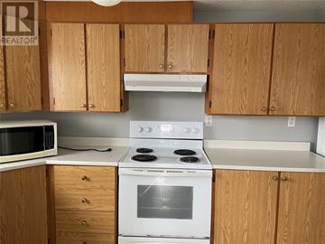 St. John's multi-family for rent - A kitchen with wooden cabinets and a white stove top oven.