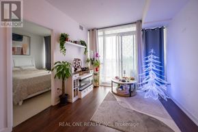 Toronto (Bayview Village) condo for rent - A bedroom with a bed, a table with a plant, and a window with a blue curtain.
