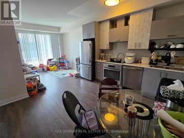 Markham (Unionville) condo for rent - A kitchen with a table and chairs in the foreground and a messy room in the background.