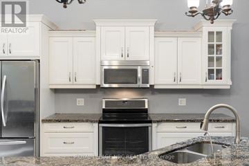 St. Catharines (Lakeshore) apartment for rent - A kitchen with white cabinets and a black stove top oven.