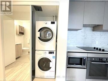 Toronto (Waterfront Communities) condo for rent - A modern kitchen with a washer and dryer built into the cabinetry.