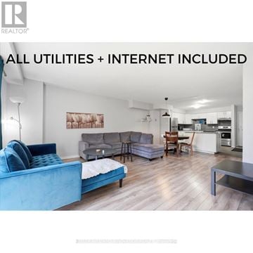 Waterloo townhouse for rent - A living room with a blue couch and a kitchen area in the background.