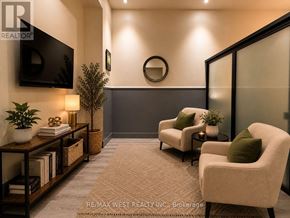 Hamilton (Beasley) condo for rent - A living room with a flat screen TV mounted on the wall and two armchairs with green cushions.
