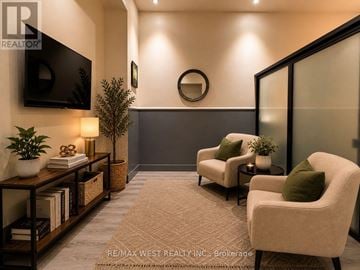 Hamilton (Beasley) condo for rent - A living room with a flat screen TV mounted on the wall and two armchairs with green cushions.