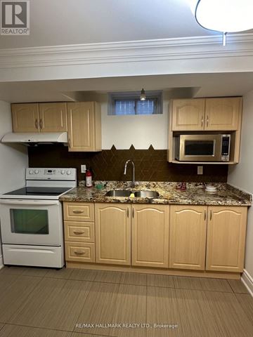 Toronto (Rustic) apartment for rent - A kitchen with a white oven and microwave, a sink, and wooden cabinets.