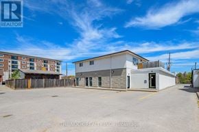 Oshawa (Centennial) condo for rent - A real estate company's office is located in a parking lot with a building in the background.