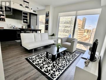 Toronto (Bay Street Corridor) condo for rent - A modern living room with a white sofa and a black and white rug.