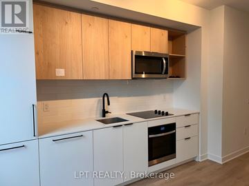 Toronto (Dovercourt-Wallace Emerson-Junction) condo for rent - A kitchen with white cabinets and a microwave above the stove.