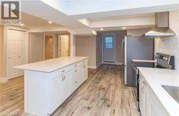 Dundas apartment for rent - A modern kitchen with white cabinets and a wooden floor.