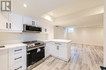 Georgina (Keswick South) apartment for rent - A white kitchen with a stove top oven and microwave.