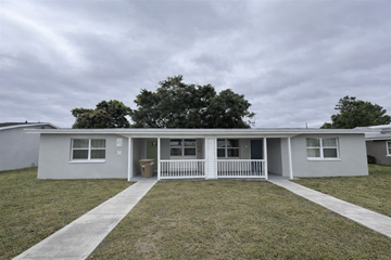 Cape Coral apartment for rent - A grey house with a white fence and a green tree in the background.