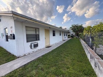 Fort Lauderdale apartment for rent - A white building with a yellow door and a sign that says "STOP" on the window.