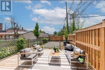 Toronto (Dovercourt-Wallace Emerson-Junction) duplex for rent - A wooden deck with a couch and a coffee table is surrounded by a fence.