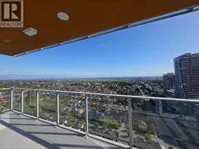 Vancouver apartment for rent - A balcony with a metal railing overlooks a cityscape.