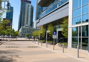 Toronto (Waterfront Communities) condo for rent - A building with a glass facade is surrounded by a metal fence and a sign that reads "RE/MAX HALLMARK REALTY LTD. Brokerage".