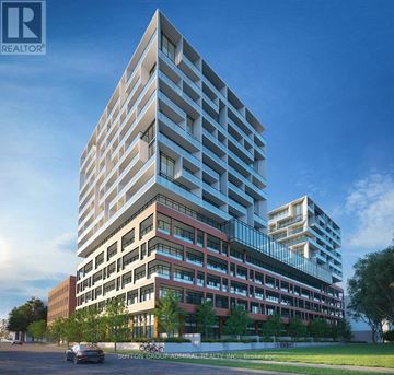 Toronto (Niagara) condo for rent - A modern multi-story building with a glass facade and a car parked in front.