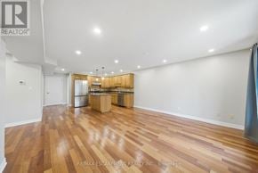 Brant (Paris) condo for rent - A spacious room with wooden flooring and a kitchen area in the background.