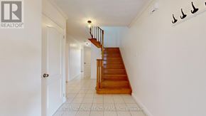 Markham (Middlefield) apartment for rent - A white hallway with a wooden staircase and a white door.