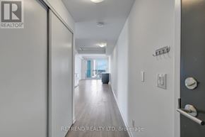 Kitchener condo for rent - A hallway with a door on the left and a window in the distance.
