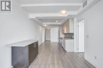 Kitchener condo for rent - A spacious kitchen with white cabinets and a wooden floor.