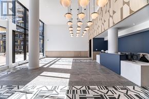 Burlington (Alton) condo for rent - A modern office lobby with a geometric patterned floor and a series of hanging lights.