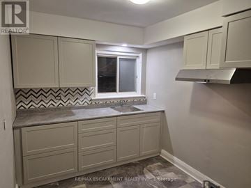 Niagara Falls (Downtown) multi-family for rent - A kitchen with beige cabinets and a patterned tile backsplash.