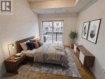 Kitchener townhouse for rent - A bedroom with a large bed, a nightstand with a lamp, and a window overlooking a balcony.