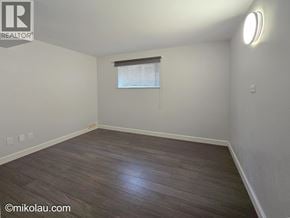 Burnaby apartment for rent - A room with wooden flooring and a window with blinds.