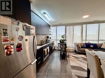 Toronto (Flemingdon Park) condo for rent - A modern kitchen with a refrigerator covered in magnets and a dining area with a striped rug.