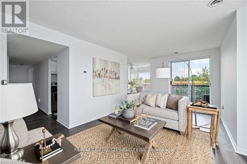 London North (North I) condo for rent - A well-lit living room with a white couch, a coffee table, and a painting on the wall.