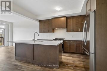 Hamilton (Waterdown) townhouse for rent - A modern kitchen with wooden cabinets and a white countertop.