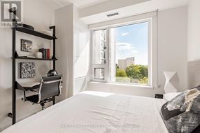 Toronto (Mount Pleasant West) condo for rent - A bedroom with a large bed, a desk with a chair, and a window overlooking a cityscape.