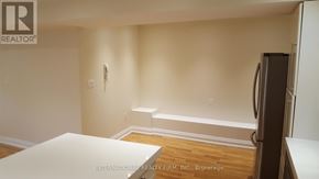 Toronto (Yonge-St. Clair) triplex for rent - A white table is in the middle of a room with a refrigerator on the right.