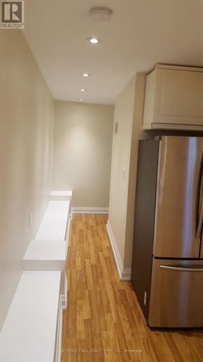 Toronto (Yonge-St. Clair) triplex for rent - A stainless steel refrigerator in a kitchen with wooden floors and white walls.