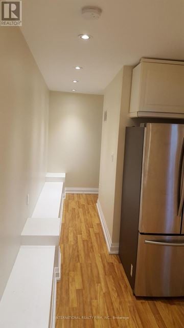 Toronto (Yonge-St. Clair) triplex for rent - A stainless steel refrigerator in a kitchen with wooden floors and white walls.