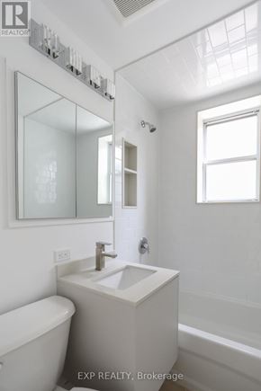 Toronto (East End-Danforth) triplex for rent - A white bathroom with a tub, sink, and mirror.
