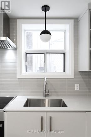 Toronto (East End-Danforth) triplex for rent - A modern kitchen with EXP Realty Brokerage written on the sink.