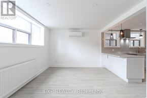 Toronto (East End-Danforth) triplex for rent - A spacious room with a window, a radiator, and a kitchenette.