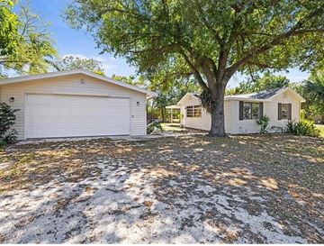 Fort Myers apartment for rent - A house with a white garage door is surrounded by trees.
