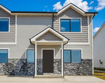 Urbandale apartment for rent - A modern house with a stone wall and a black door.