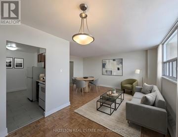 Toronto (Victoria Village) condo for rent - A living room with a grey couch, a coffee table, and a dining table with chairs.