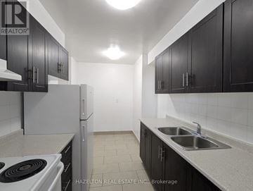 Toronto (Victoria Village) condo for rent - A kitchen with black cabinets and a white stove top oven.