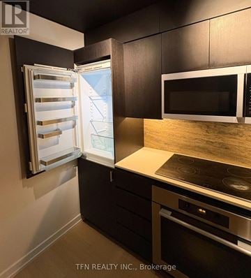Toronto (Waterfront Communities) condo for rent - A kitchen with a stove top oven and a refrigerator with the door open.
