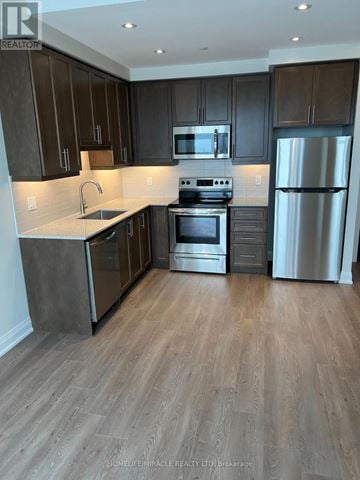 Brampton (Queen Street Corridor) condo for rent - A kitchen with dark wood cabinets and stainless steel appliances.