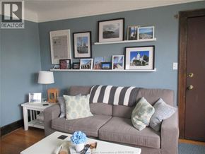 Windsor apartment for rent - A living room with a grey couch, a white coffee table, and a wall with framed pictures.
