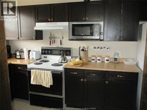 Windsor apartment for rent - A kitchen with black cabinets and a white stove top.