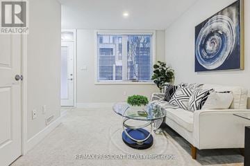 London North (North E) townhouse for rent - A living room with a white couch, a glass coffee table, and a large abstract painting on the wall.